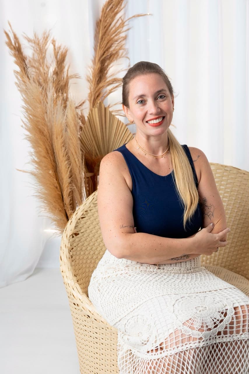 Gabriela Moreira, da Vita Saúde, sorrindo sentada em uma poltrona de fibra natural